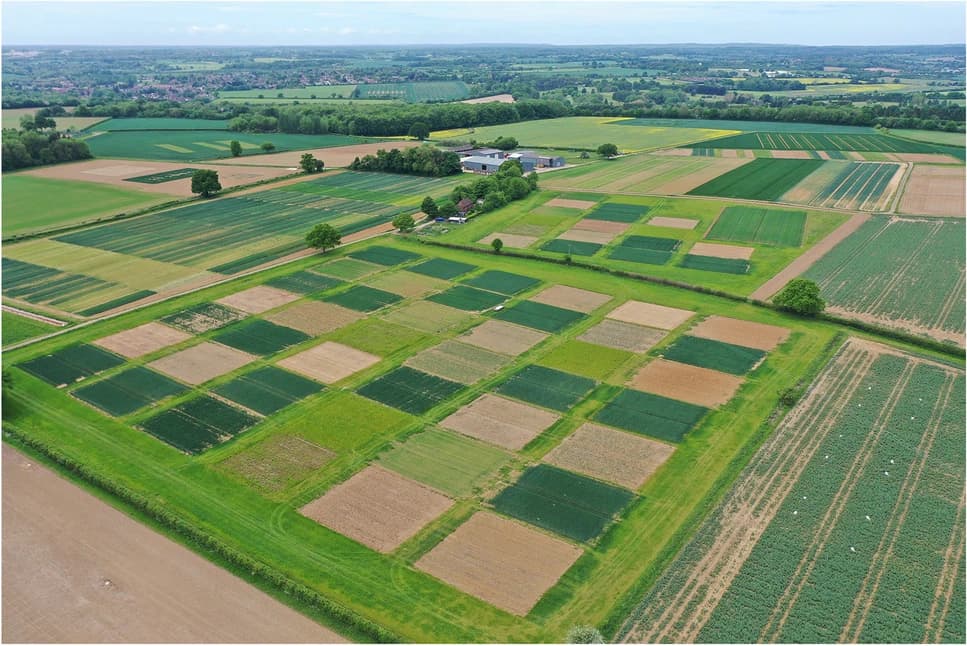 Aerial photograph of the Large-Scale Rotation Experiment at Rothamsted Research, showing dozens of square field plots in different crops laid out in a regular grid across the landscape.